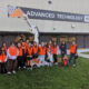 Davie county students in orange safety vests pose outside the Ashley Furniture building on their visit to the facility on Manufacturing day.