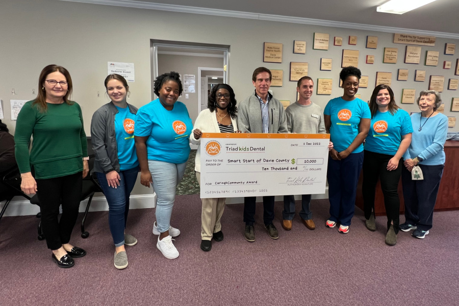 (Left to Right) Susan Domanski, Jenna Stottler, Jessica Ford, Charlene Jones, Rick Cross, Thomas Johnson,  Dr. Kasheena Hollis, DMD, Renee Young, and Ruth Hoyle. triad Kids' Dental presents Smart Start of Davie County with a check for $10,000. 